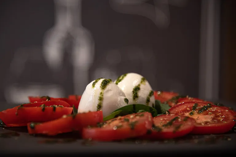 Mozzarella de búfala, tomate e manjericão sobre fundo escuro