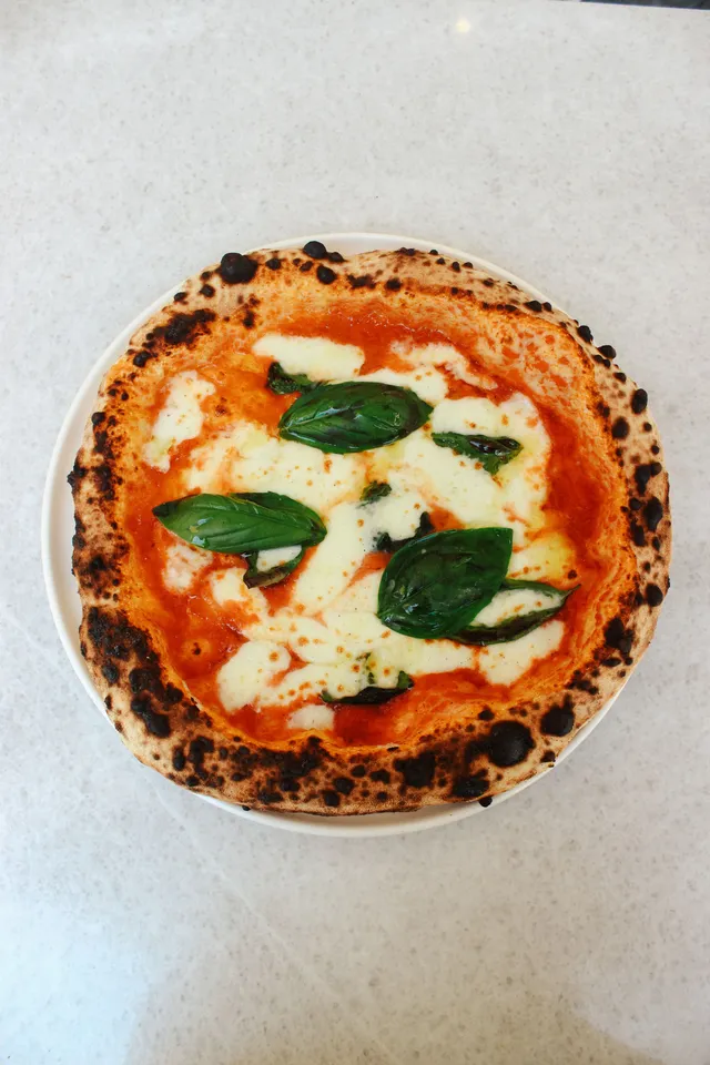 Pizza margherita inteira vista de cima, bordas tostadas no forno a lenha